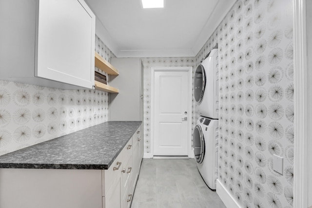 washroom with cabinets and stacked washer / drying machine