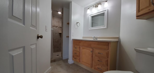 bathroom with toilet, vanity, tile patterned flooring, and a tile shower