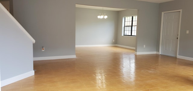 unfurnished room featuring a chandelier and light hardwood / wood-style flooring