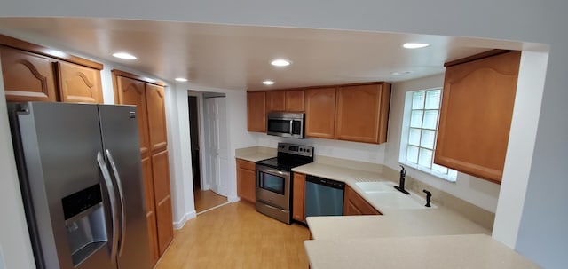 kitchen featuring sink, a wealth of natural light, stainless steel appliances, and light wood-type flooring