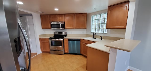 kitchen featuring light hardwood / wood-style floors, sink, appliances with stainless steel finishes, and kitchen peninsula