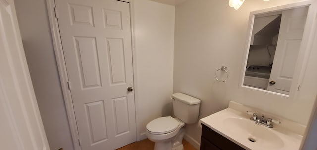 bathroom featuring toilet, vanity, and washer / clothes dryer