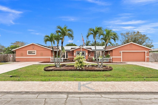 ranch-style home featuring driveway, a front lawn, solar panels, and stucco siding