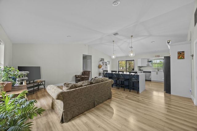 living room with sink, light hardwood / wood-style floors, and vaulted ceiling