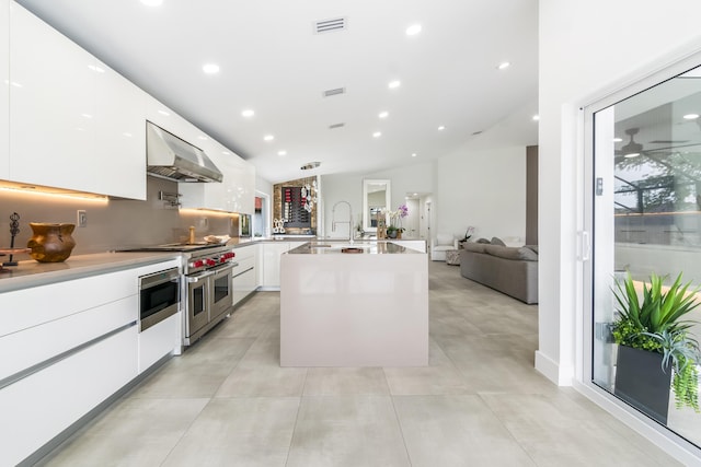 kitchen with sink, white cabinetry, tasteful backsplash, stainless steel appliances, and a kitchen island with sink