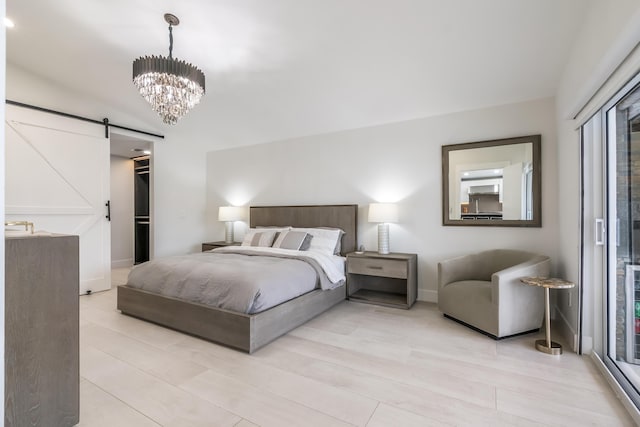 bedroom with a barn door, a chandelier, light hardwood / wood-style flooring, and a spacious closet