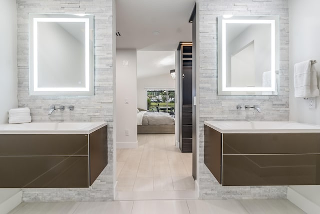 bathroom with vanity, tile patterned flooring, and vaulted ceiling