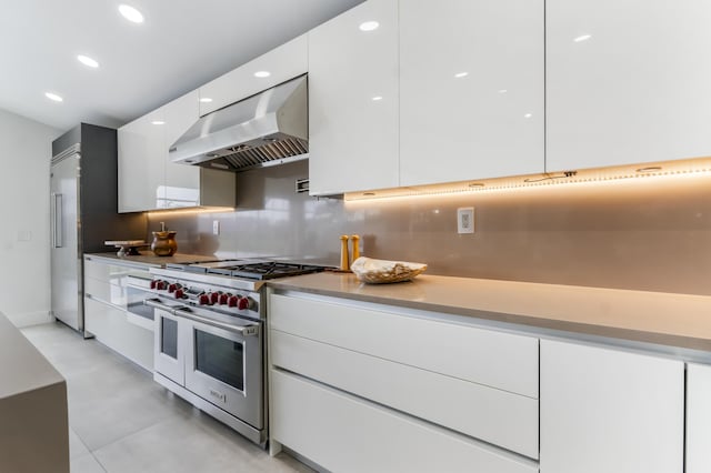 kitchen featuring premium appliances, decorative backsplash, ventilation hood, and white cabinets