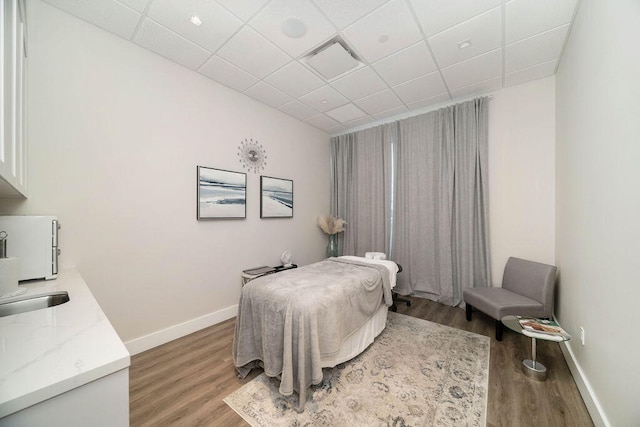 bedroom featuring a paneled ceiling and wood-type flooring