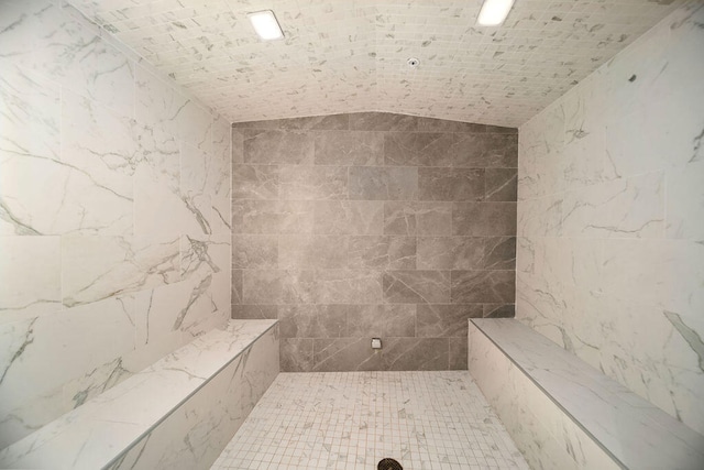 bathroom featuring a tile shower, brick ceiling, and lofted ceiling