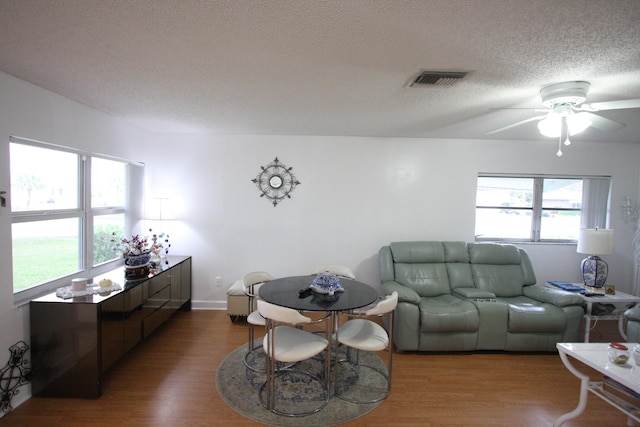 living room with hardwood / wood-style flooring, ceiling fan, and a textured ceiling