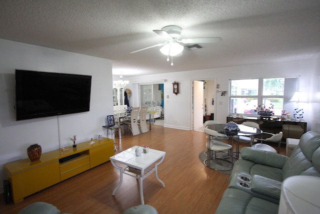 living room with ceiling fan with notable chandelier, a textured ceiling, and wood-type flooring