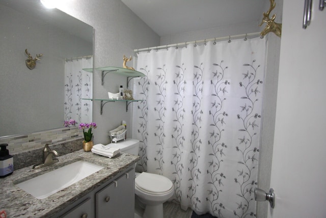 bathroom featuring toilet, tasteful backsplash, walk in shower, and vanity