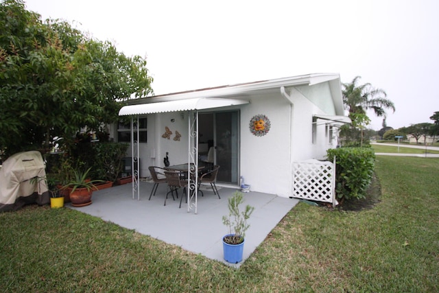 rear view of house with a patio and a lawn