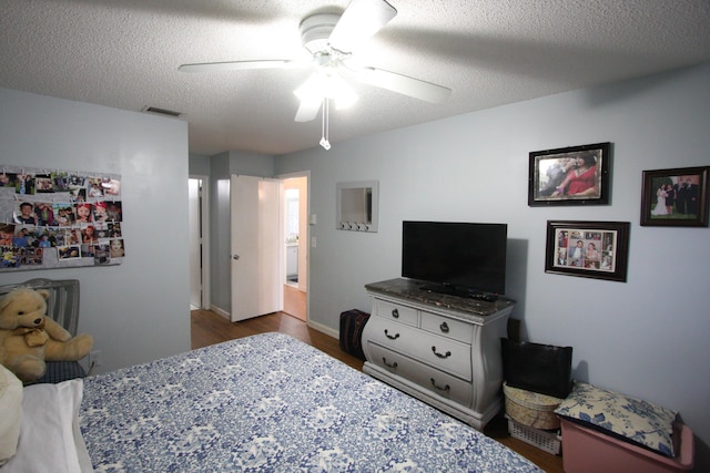 bedroom featuring ceiling fan, dark wood-type flooring, and a textured ceiling