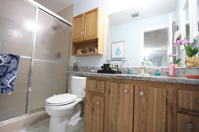 bathroom with toilet, tile patterned flooring, a shower with shower door, and vanity