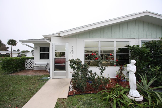 entrance to property with a lawn and a patio