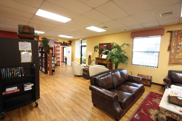 living room featuring a drop ceiling and light hardwood / wood-style flooring