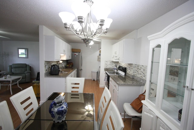 dining space featuring sink, a chandelier, a textured ceiling, and wood-type flooring