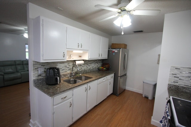 kitchen with stainless steel fridge, sink, white cabinetry, electric stove, and decorative backsplash