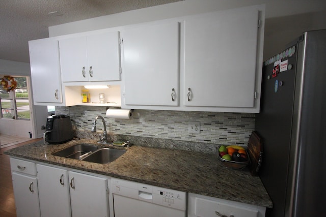 kitchen featuring white dishwasher, white cabinetry, stainless steel refrigerator, decorative backsplash, and sink