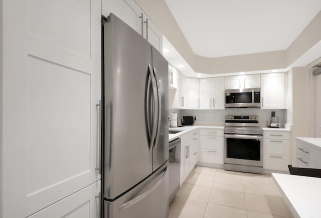 kitchen with white cabinetry, appliances with stainless steel finishes, light tile patterned flooring, and backsplash