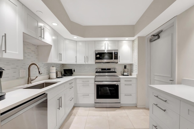 kitchen with sink, stainless steel appliances, white cabinets, light tile patterned flooring, and decorative backsplash