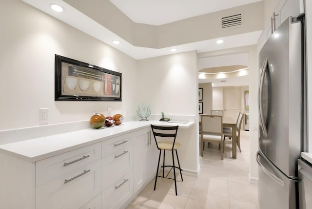 kitchen featuring white cabinetry, light tile patterned floors, and stainless steel refrigerator