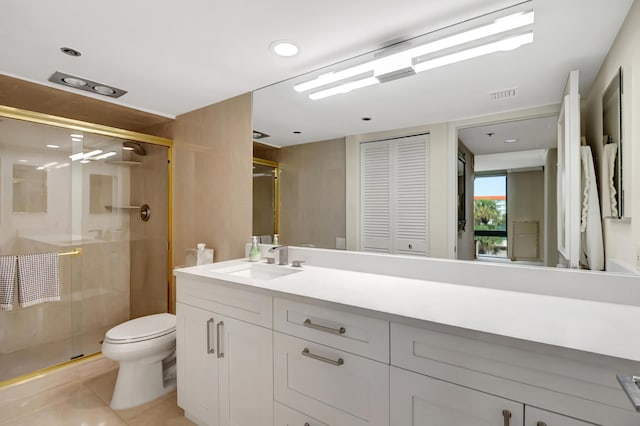 bathroom with tile patterned flooring, vanity, a shower with shower door, and toilet