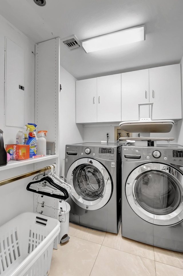 clothes washing area featuring cabinets, washing machine and dryer, and light tile patterned floors