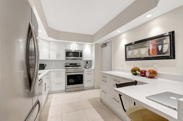 kitchen featuring appliances with stainless steel finishes, light tile patterned floors, white cabinets, and decorative backsplash