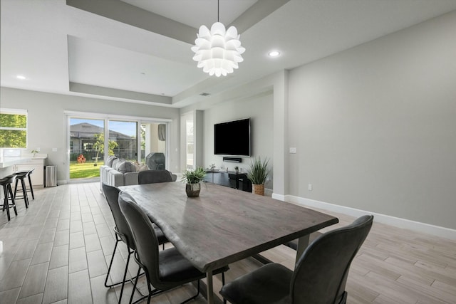 dining space featuring an inviting chandelier and a raised ceiling