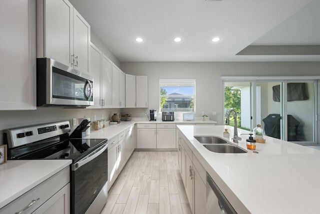 kitchen with sink, white cabinets, appliances with stainless steel finishes, and light hardwood / wood-style flooring