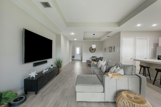 living room featuring a tray ceiling and light hardwood / wood-style flooring