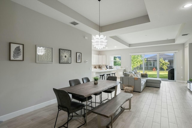 dining area featuring a chandelier and a raised ceiling