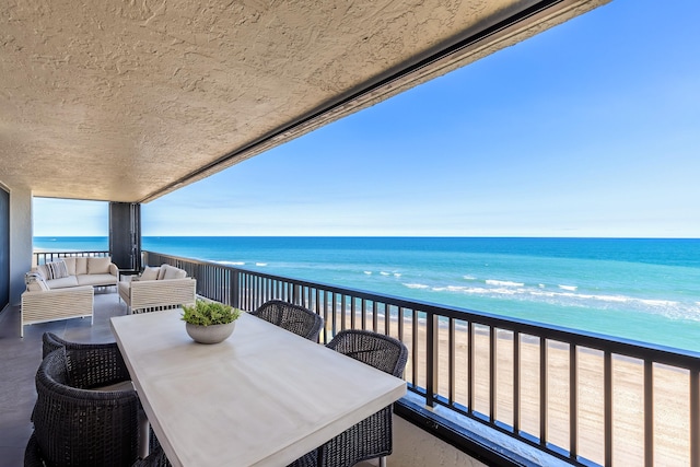 balcony with a water view, a beach view, and outdoor lounge area