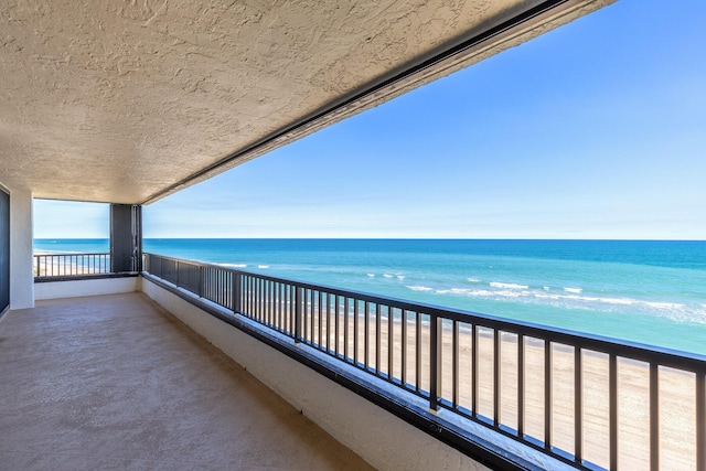 balcony with a water view and a beach view