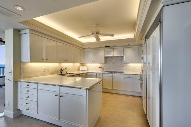 kitchen with sink, black electric stovetop, white cabinets, and a tray ceiling