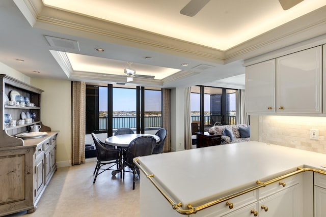 kitchen with a wealth of natural light, a raised ceiling, and white cabinets