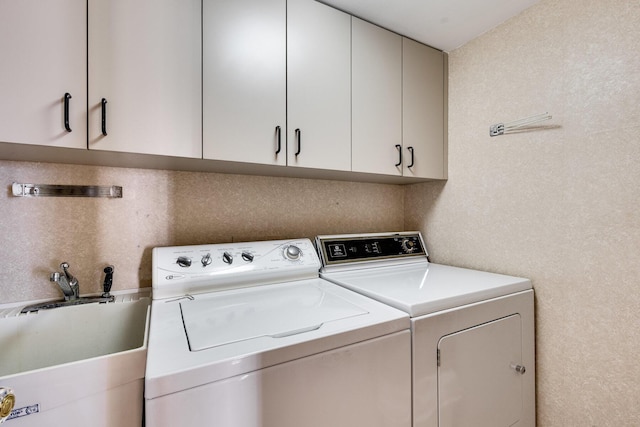 clothes washing area with cabinets, sink, and independent washer and dryer