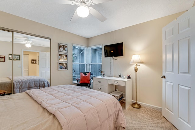 bedroom with ceiling fan, light carpet, a closet, and a textured ceiling