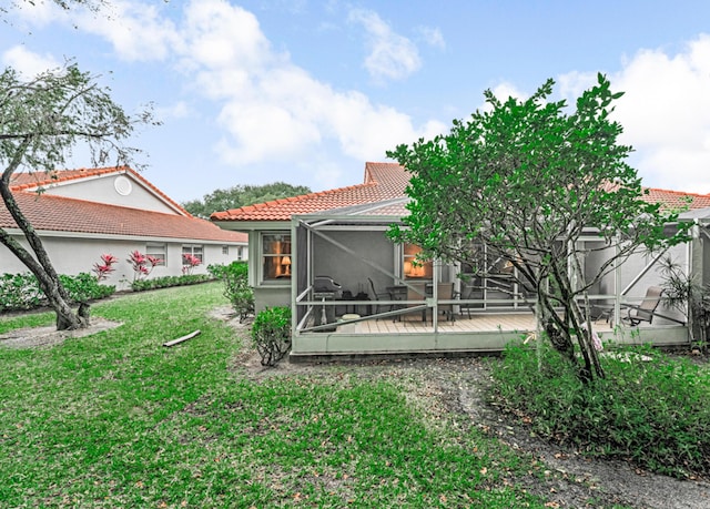 back of property with a lanai, a lawn, and a wooden deck