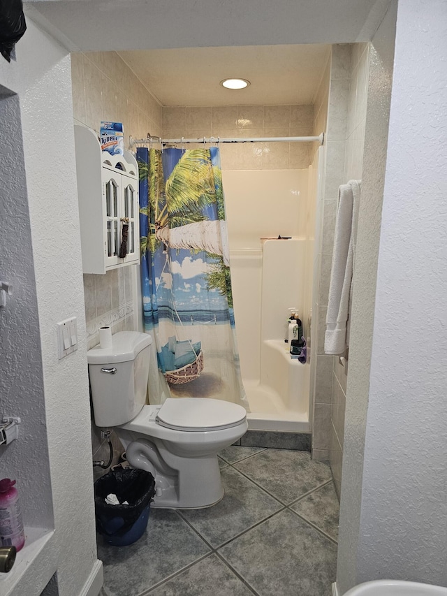 bathroom with toilet, tile walls, tile patterned floors, and a shower with shower curtain