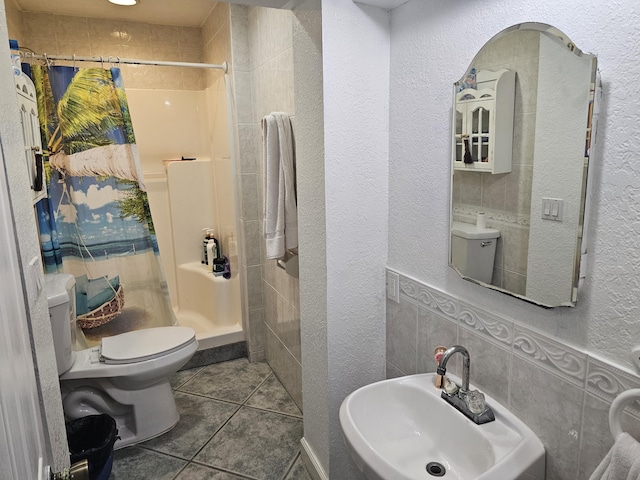 bathroom featuring toilet, tile walls, tile patterned floors, a shower with curtain, and sink