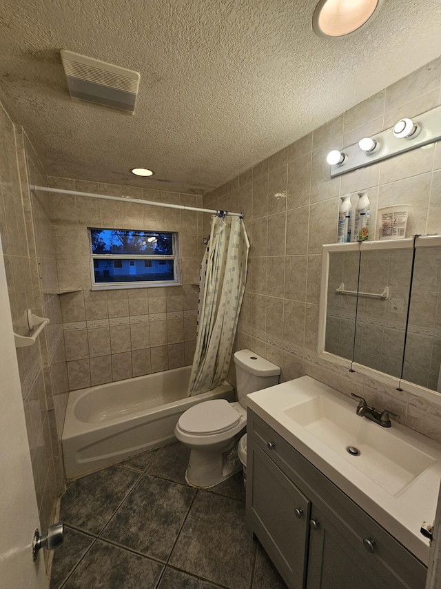 full bathroom with shower / tub combo with curtain, tile patterned flooring, tile walls, a textured ceiling, and vanity