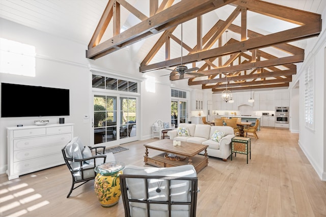 living room with beamed ceiling, ceiling fan with notable chandelier, high vaulted ceiling, and light wood-type flooring