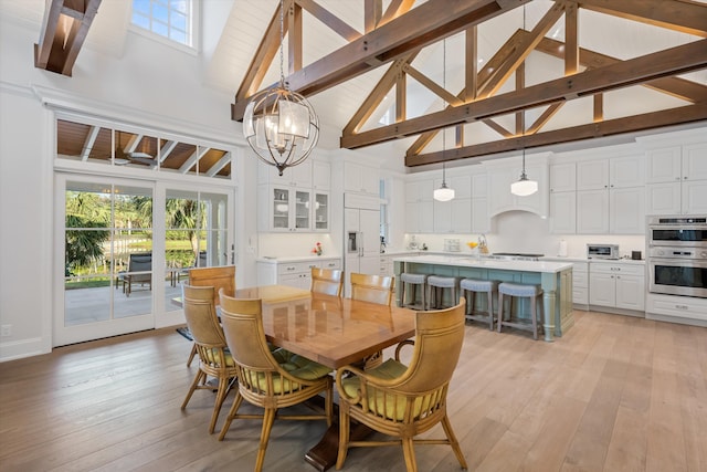 dining space with beamed ceiling, a chandelier, high vaulted ceiling, and light wood-type flooring