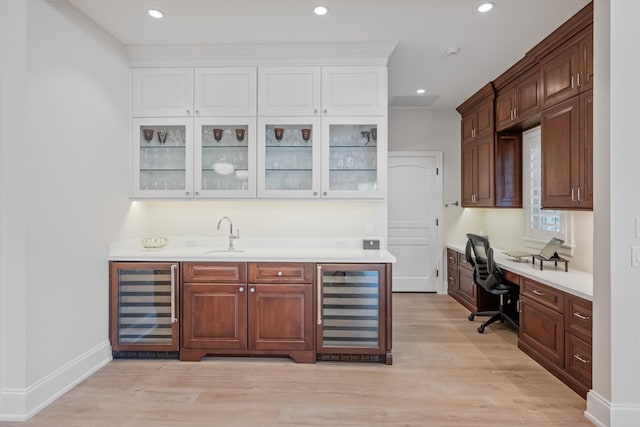 bar featuring sink, beverage cooler, and light hardwood / wood-style floors