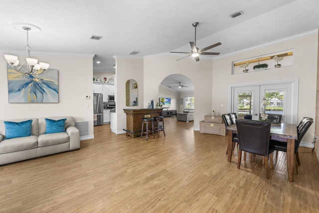 dining room with vaulted ceiling, ceiling fan with notable chandelier, crown molding, light wood-type flooring, and french doors