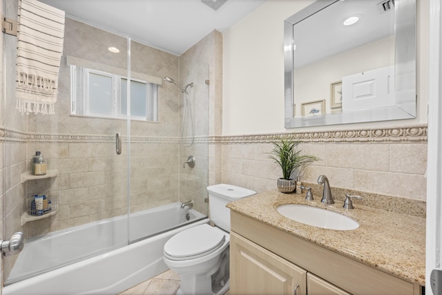 full bathroom with toilet, tile walls, vanity, enclosed tub / shower combo, and tile patterned flooring